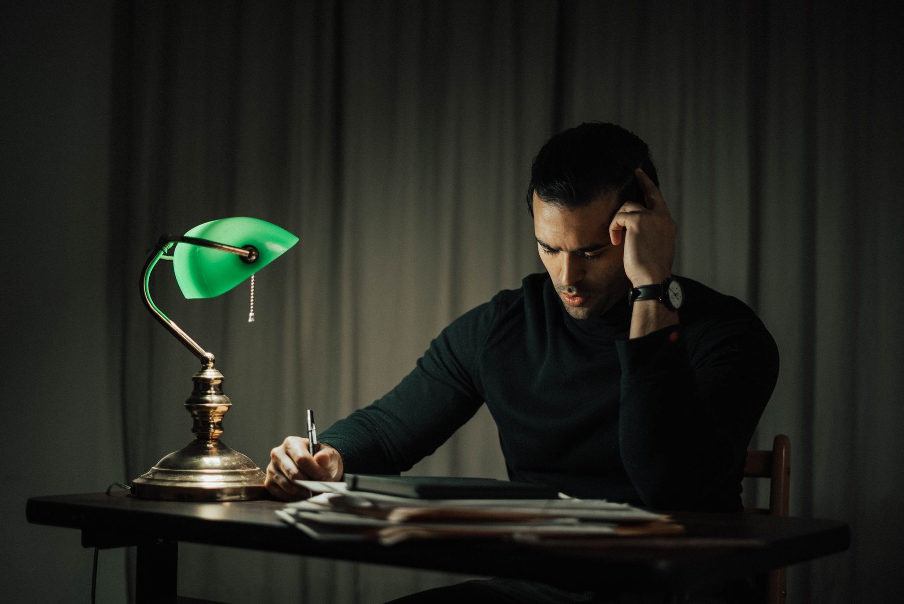 A focused person writing at a desk late at night