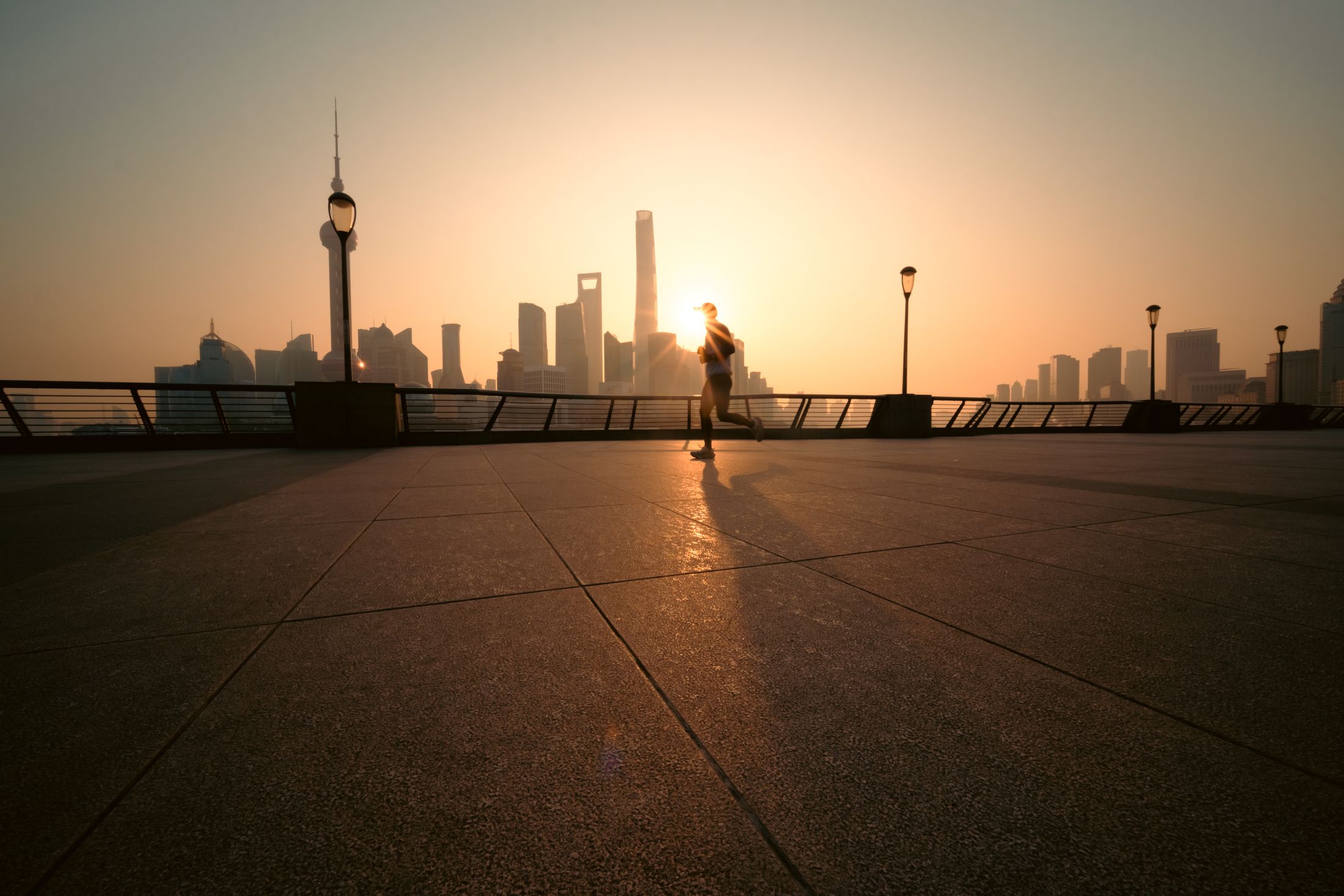 A runner moving along a city waterfront at sunrise