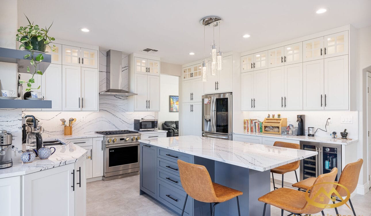 Open-concept kitchen with white and blue cabinetry, marble countertops, and pendant lighting